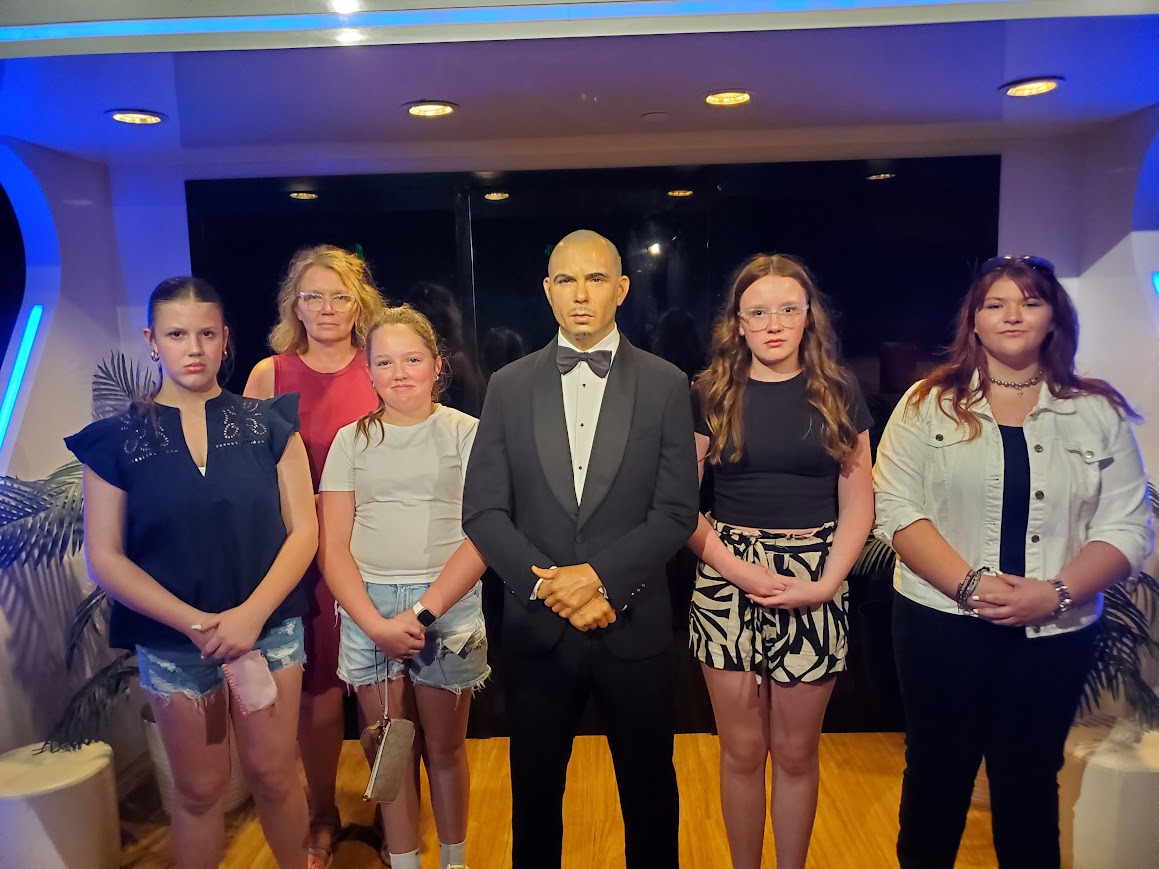 2025 NLC Qualifiers Making Serious Faces Next to a Figure of Pitbull at a Wax Museum